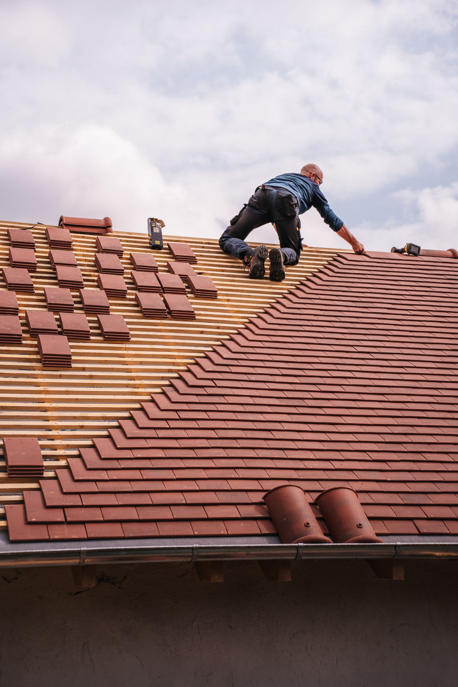 Couvreur seul posant des tuiles sur une toiture