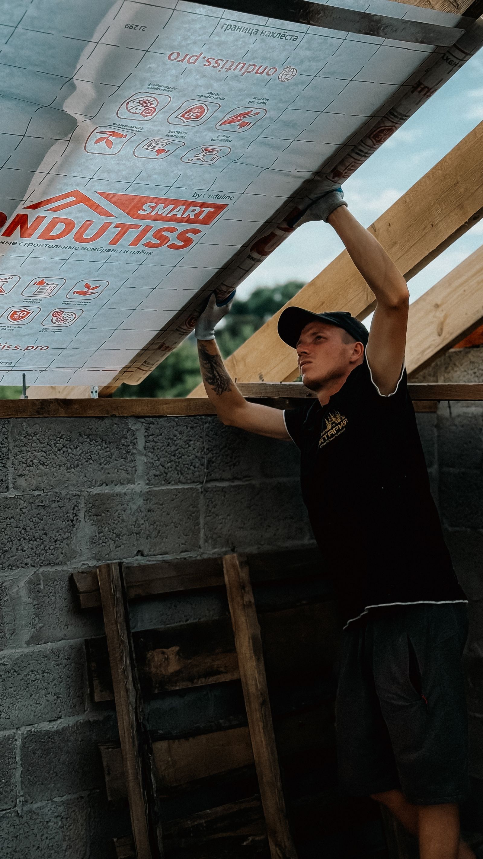 Artisan seul installant une membrane d’isolation sous toiture